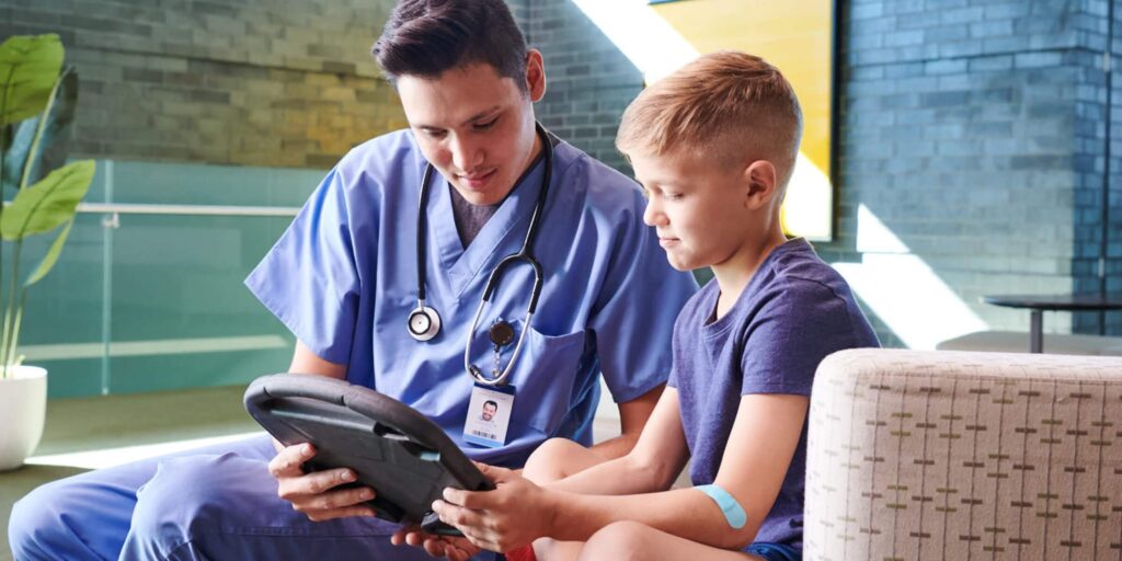 Healthcare Provider looking at a device with a boy