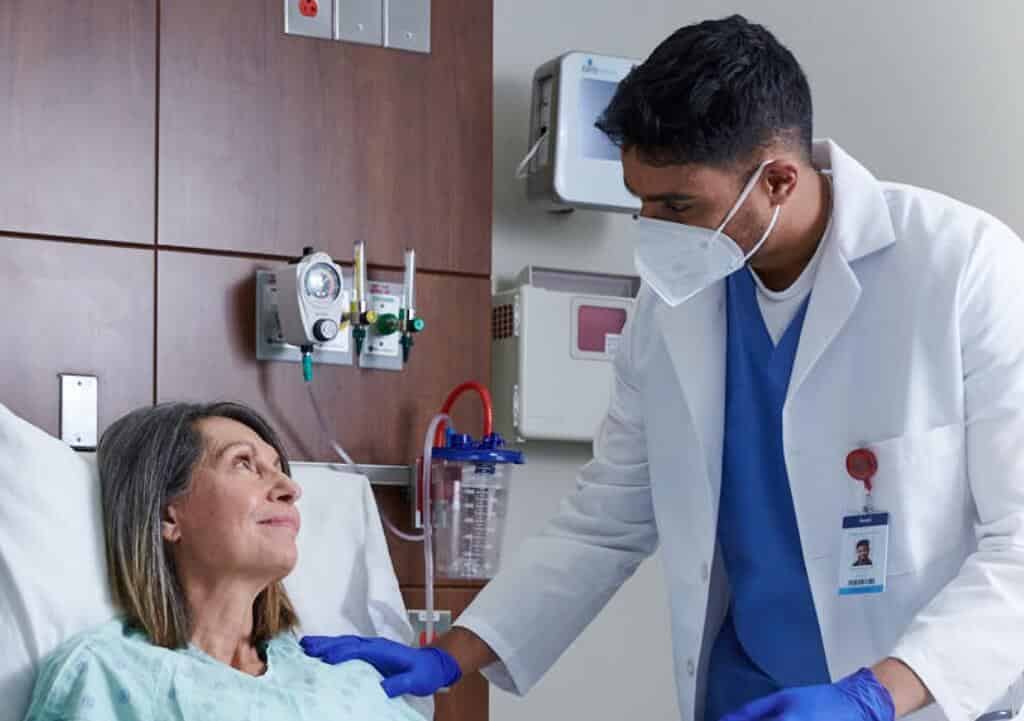 Doctor standing with patient in bed